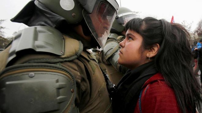 Una joven se enfrenta a un policía en una protesta