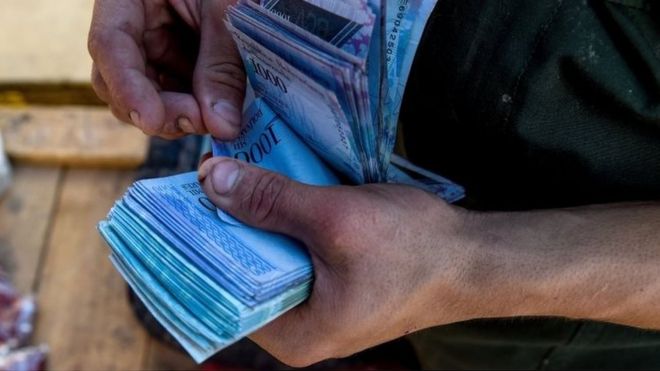 Мужчина считает 1000-боливарские купюры, чтобы купить продукты на муниципальном рынке Coche, окрестности Каракаса, 20 июня 2018 года