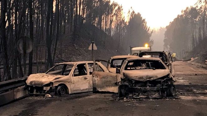 Сгоревшие автомобили видны на местной дороге во время лесного пожара возле Педрогао Гранде