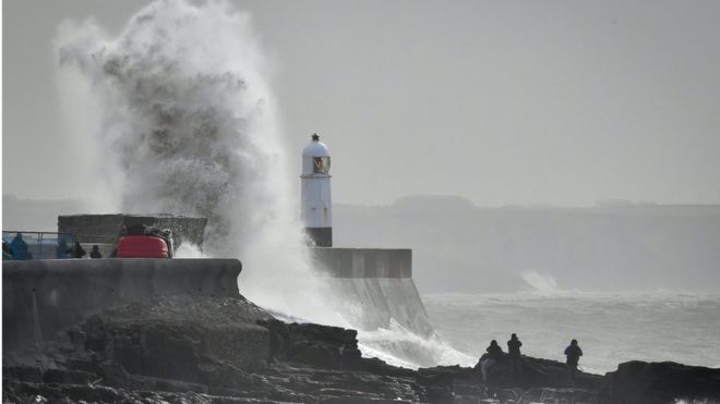 Волна шлепается о стену гавани в Porthcawl, Уэльс