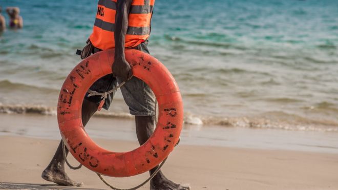 Спасатель держит спасательный круг на пляже в Лагосе, Нигерия
