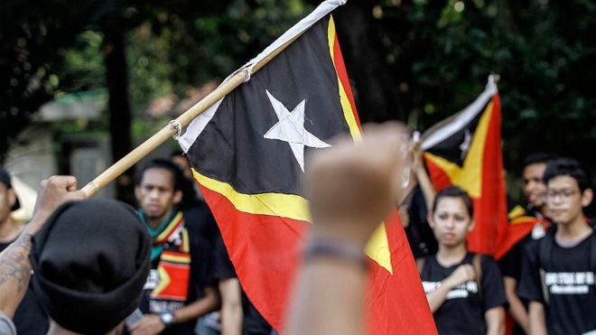 Флаг Восточного Тимора несет толпа, протестующая против Австралии