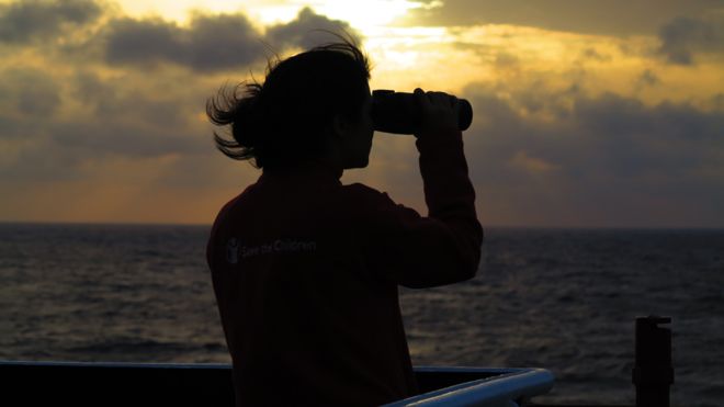 Волонтер смотрит в море в бинокль