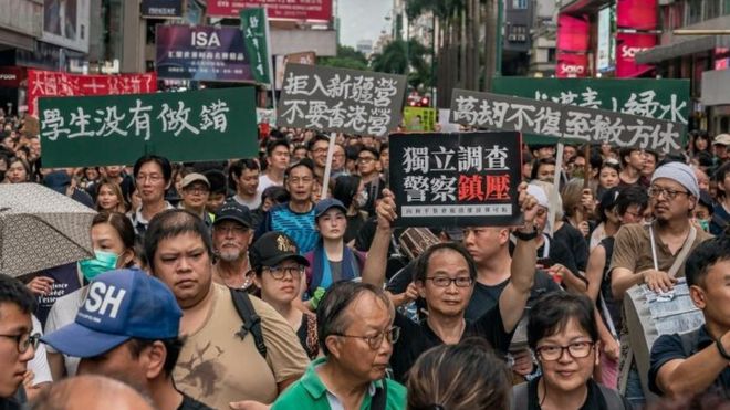 Протестующие держат плакаты и выкрикивают лозунги во время митинга на улице 7 июля 2019 года в Гонконге
