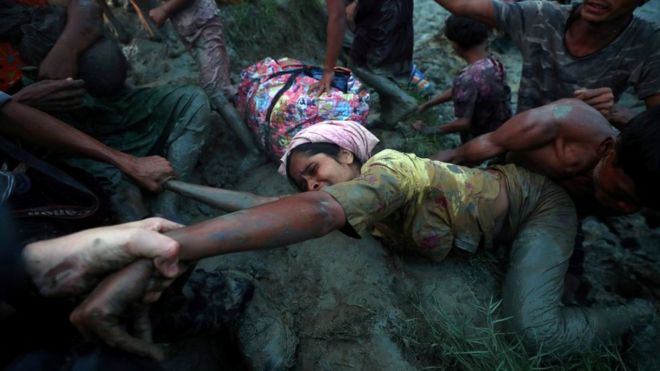 Photographers help a Rohingya Muslim to come out of Naf River.