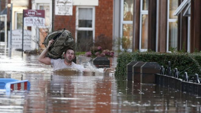 Мужчина пробирается через паводковые воды на жилой улице в Карлайле