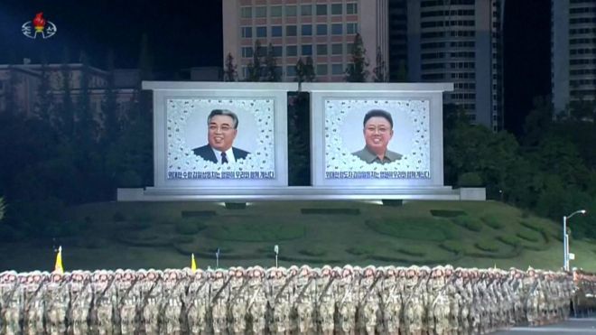 Солдаты стоят перед изображениями Ким Ир Сена и Ким Чен Ира
