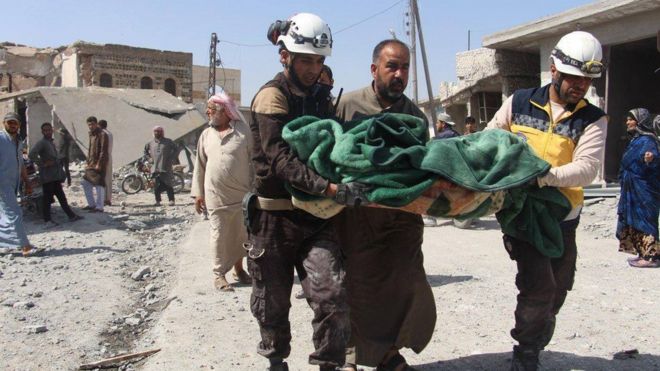Спасатели гражданской обороны Сирии помогают нести тело жертвы авиаудара в Рас-эль-Айн, провинция Идлиб, о котором сообщалось, 7 мая 2019 года