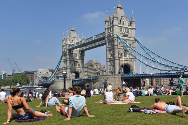 People in sun next to Tower Bridge