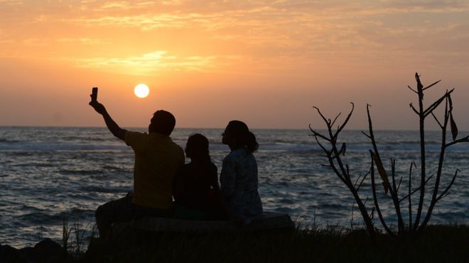 Шри-ланкийская семья делает селфи на закате солнца на пляже в Коломбо