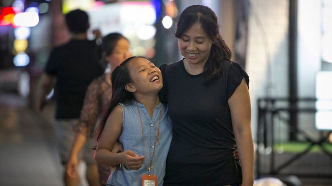 Ли Таэрим, 10 лет (слева), и ее мать Ким Мин Чжон (справа) улыбаются, когда они возвращаются домой из школы танцев ночью 10 августа 2016 года в Сеуле,