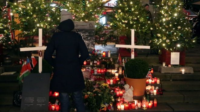 Женщина смотрит на мемориал на рождественской ярмарке на площади Брайтшайдплац