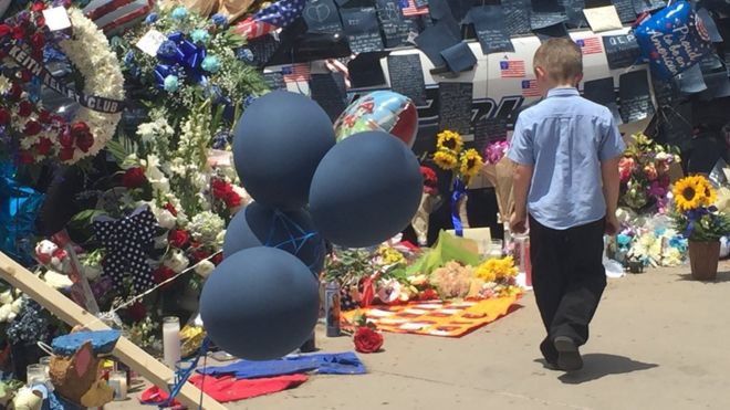 Мальчик смотрит на цветы перед штаб-квартирой полиции Далласа (10 июля)
