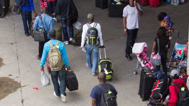 Новые заявители-беженцы прибывают на Олимпийский стадион в Монреале, Квебек.