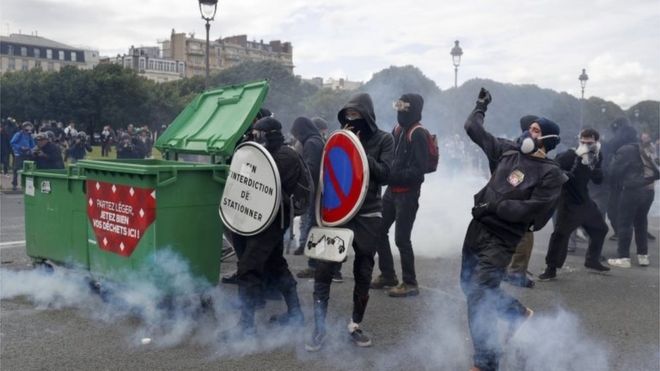 Молодые люди в масках сталкиваются с французской полицией и жандармами во время столкновений на площади Инвалидов во время демонстрации в Париже в рамках общенациональных акций протеста против планов реформирования французского трудового законодательства.