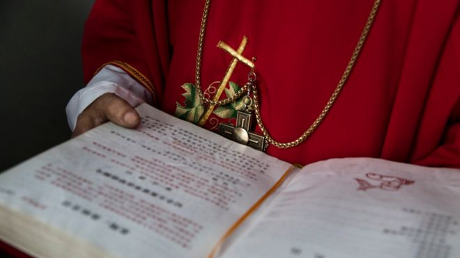 Католический дьякон из Китая держит Библию в Вербное воскресное богослужение во время Пасхальной недели, 19 апреля 2017 года.