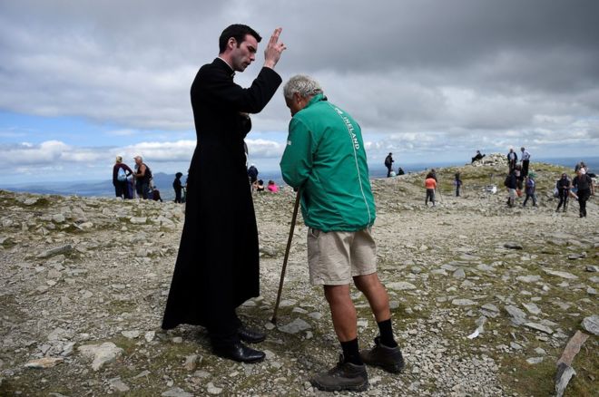 Паломник благословлен недавно рукоположенным отцом Джерардом Квирком после Мессы на вершине Кроха Патрика