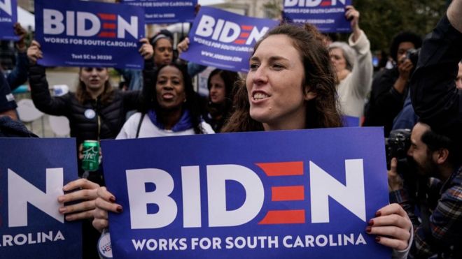 Избиратели в Южной Каролине держат плакаты в поддержку президентской кампании Джо Байдена