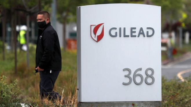 Мужчина возле вывески перед штаб-квартирой Gilead Sciences