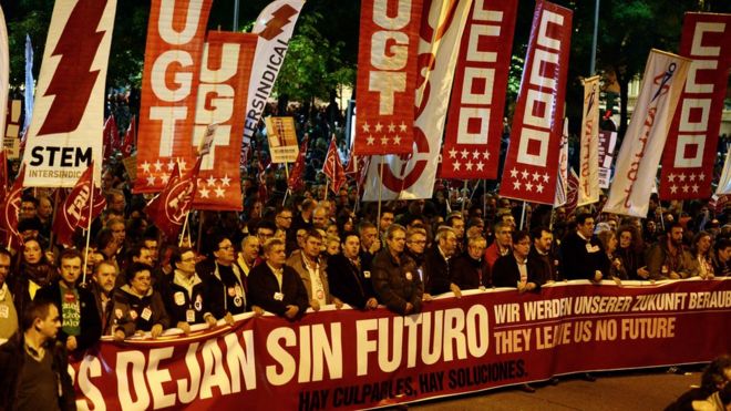 Протестующие держат гигантский баннер с надписью на испанском, английском и немецком языках: «У нас нет будущего. Есть виновники.Есть решения »