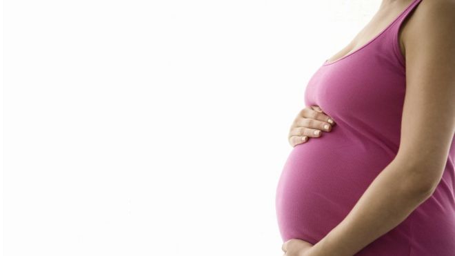 Беременная женщина касается ее живота