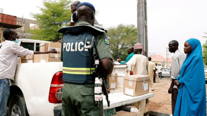 Полицейский наблюдает за тем, как сотрудники загружают ящики в грузовик во время раздачи избирательных материалов в офисе INEC в Йоле, штат Адамава, Нигерия, 15 февраля 2019 года.