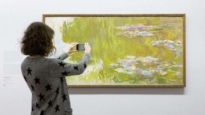 Женщина смотрит на деньги водяные лилии живопись через приложение AR