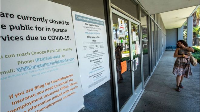 Женщина у здания закрытого офиса Департамента занятости штата Калифорния из-за коронавируса.