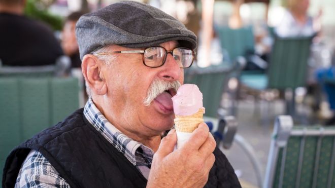Пожилой мужчина ест мороженое