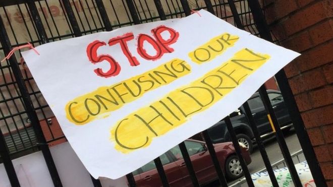 Знак «Хватит путать наших детей» на железных перилах возле школы