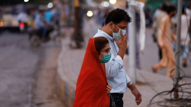 Мужчина и женщина в защитных масках гуляют по улице после того, как Пакистан снял ограничения карантина, поскольку вспышка коронавирусной болезни (COVID-19) продолжается в Карачи, Пакистан, 18 августа 2020 года.