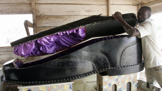 Гробовщик открывает гроб в форме обуви в своем выставочном зале в Аккре 27 января 2008 года. Индивидуальные гробы популярны в Гане и могут отражать статус и профессию покойного.