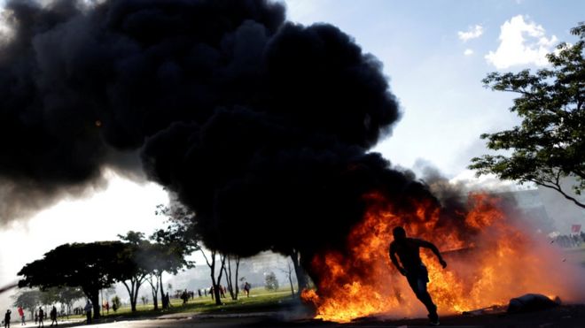 Демонстрант бежит возле горящей баррикады во время акции протеста против президента Мишеля Темера в Бразилиа, Бразилия, 24 мая 2017 года