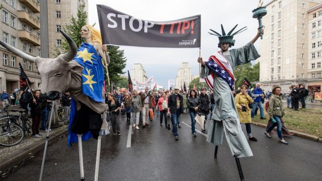 Протестующие, одетые как Америка и Европа, проводят демонстрацию против соглашений о свободной торговле TTIP и CETA 17 сентября 2016 года в Берлине, Германия.