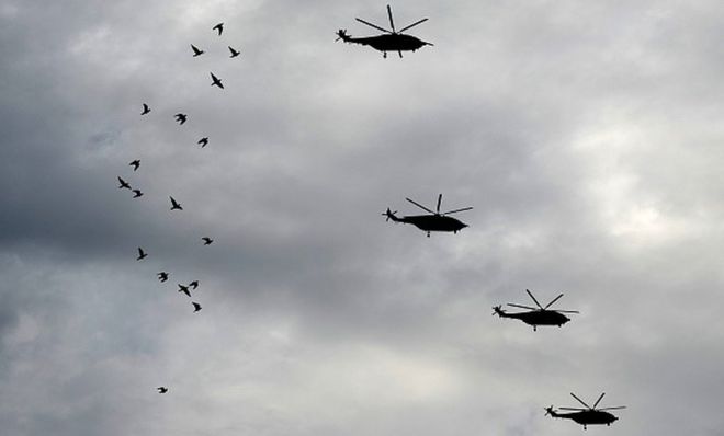 Китайские военные вертолеты, участвующие в репетиции перед военным парадом в ознаменование 70-й годовщины окончания Второй мировой войны, летят над стайкой птиц в Пекине 23 августа 2015 года