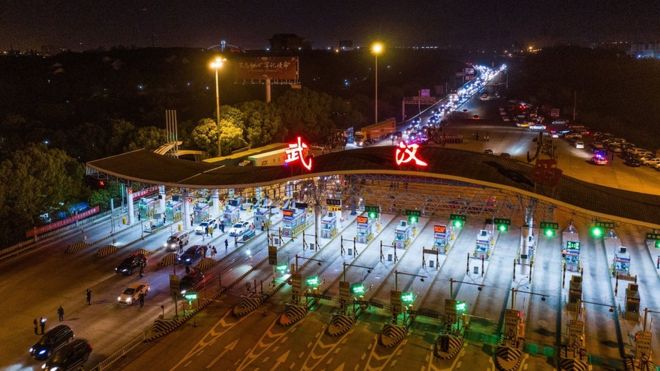 На этом аэрофотоснимке, сделанном в начале 8 апреля 2020 года, показаны автомобили, проезжающие через станцию ??взимания платы на автомагистрали в Ухане в центре Китая