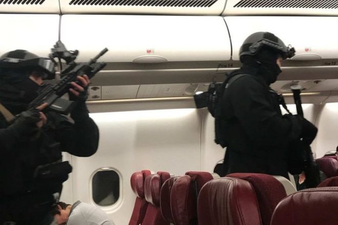 Сильно вооруженные полицейские входят в самолет после его возвращения в аэропорт Мельбурна