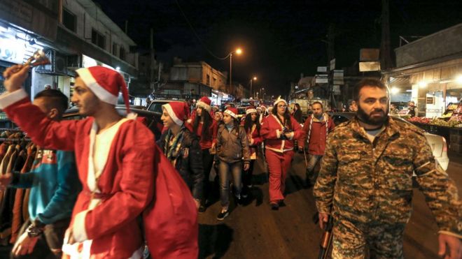 Người dân Syrian trong trang phục Giáng sinh xuống đường ở thủ đô Damascus đêm Noel 24/12/2017, được hộ tống bởi lực lượng cảnh sát Syria.