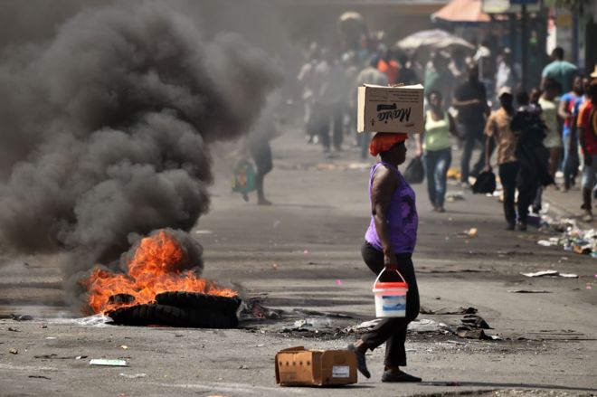 Шина, установленная небольшой группой демонстрантов, горит на улице в коммуне Петион-Виль в столице Гаити Порт-о-Пренсе