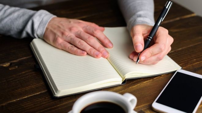 Una persona escribiendo con la mano izquierda.