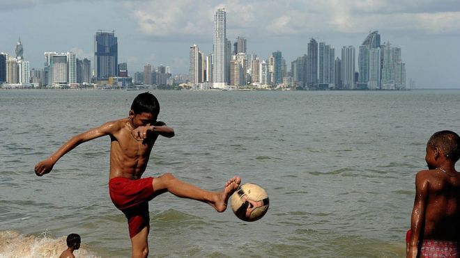 Niños panameños juegan fútbol frente a la bahía de Panamá