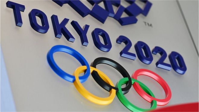 The Olympic rings and Tokyo 2020 branding are seen in relief in a wall