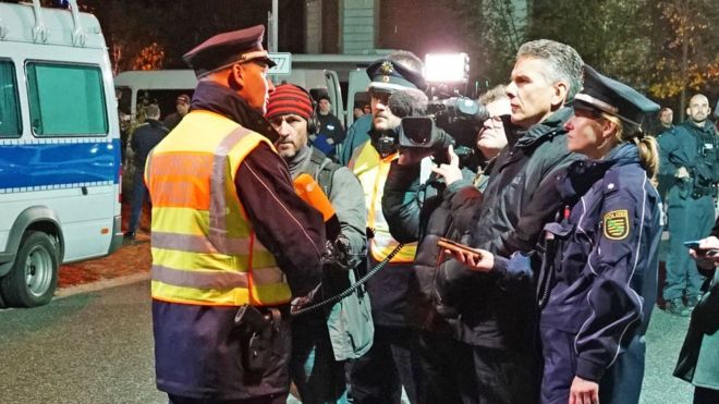 На этом групповом снимке виден полицейский брифинг ночью, когда один из офицеров обращается к видеокамере, которая профессионально приспособлена для аудио