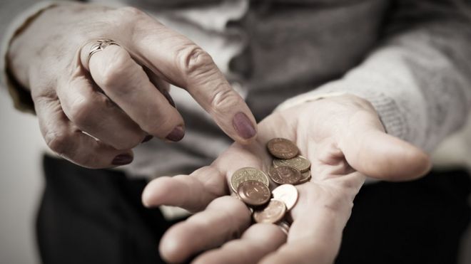 Mulher idosa com moedas na palma da mão