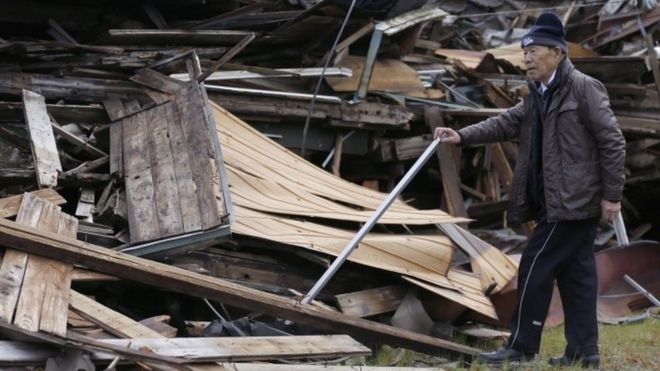Токио Миямото исследует повреждения домов, разрушенных землетрясениями в Асо, префектура Кумамото (17 апреля 2016 года)