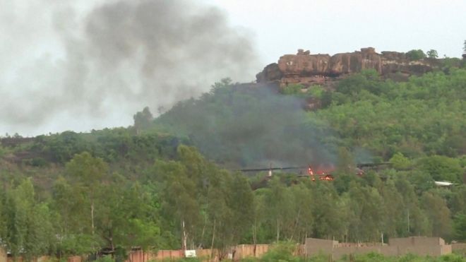 Flames rise above a forest following an attack where gunmen stormed Le Campement Kangaba resort in Dougourakoro
