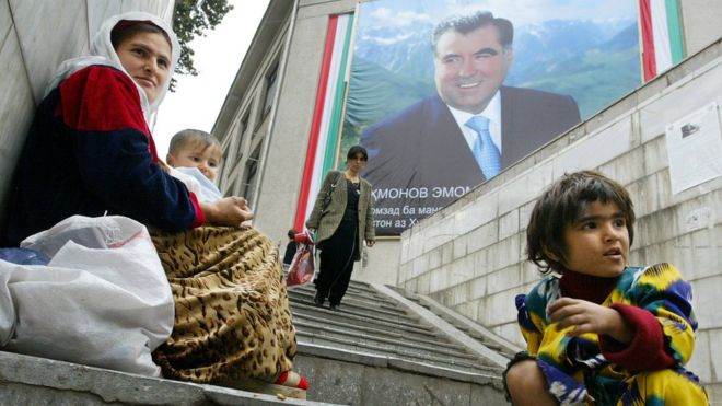 Мать и ее дети молятся на лестнице под зданием с огромным плакатом президента Таджикистана Эмомали Рахмона, 23 октября 2006 г.
