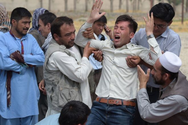 Родственнику (С) утешается, когда он плачет рядом с невидимой обувью и другими вещами тех, кто был убит в результате теракта-близнеца, в мечети в Кабуле, 24 июля