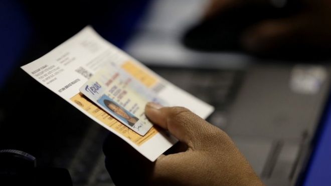 An election official checks a voter's photo ID in Austin, Texas. Photo: February 2014