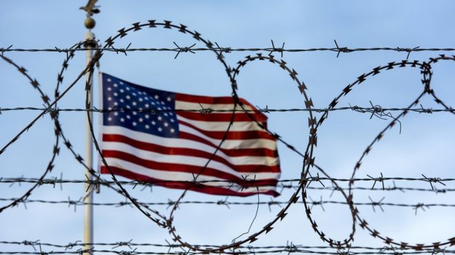 Bandeira americana por trás de uma cerca farpada na fronteira dos EUA com o México